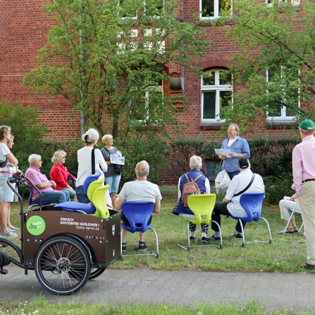 Mehrere ältere Menschen nehmen an einer Führung über das Gelände des Evangelischens Johannesstifts teil.