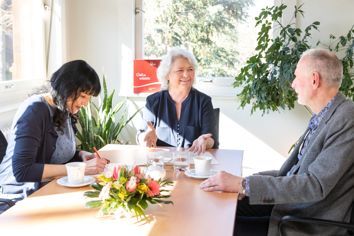 Freundeskreis: drei Menschen sitzen zusammen an einem Tisch