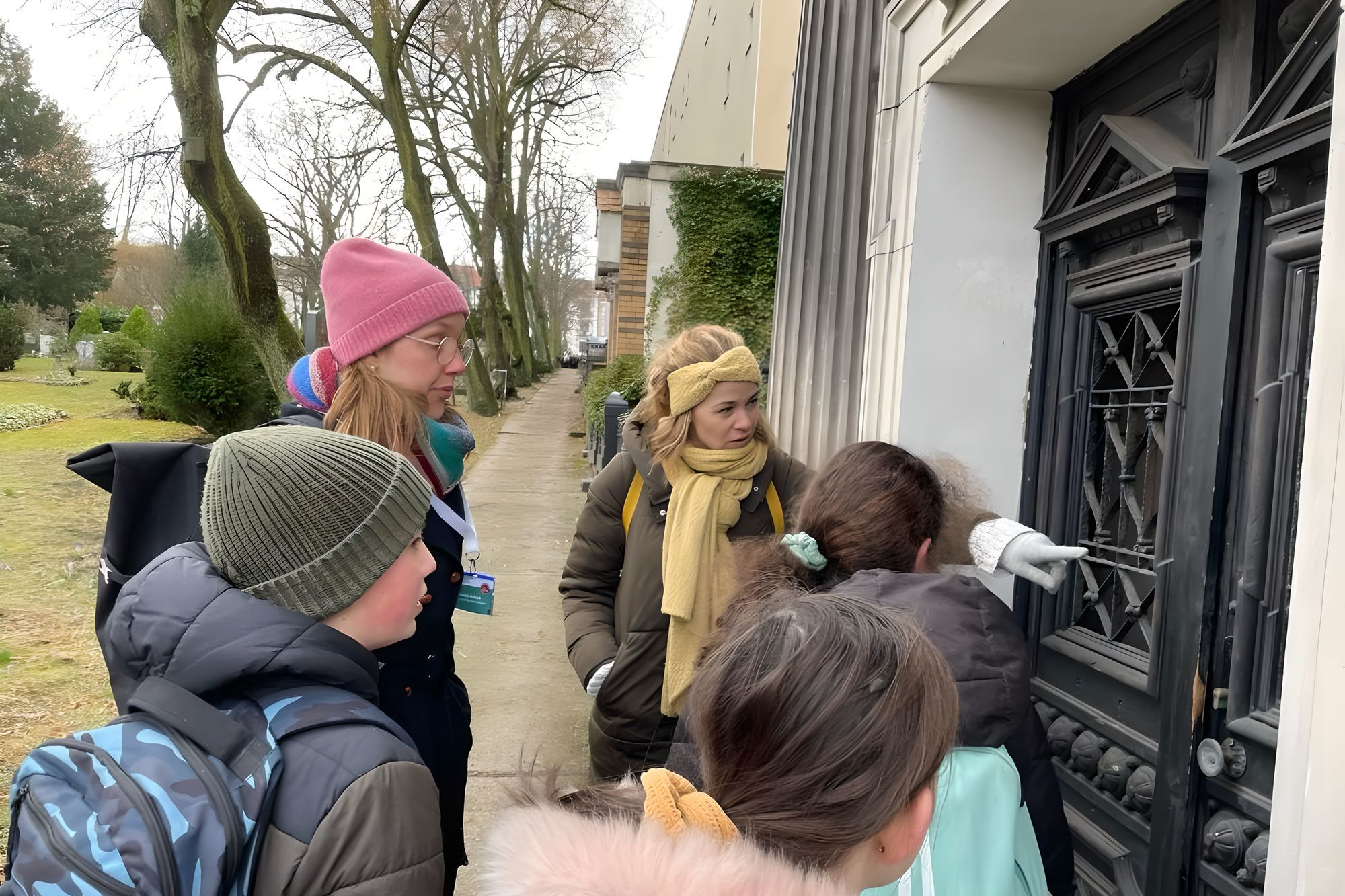 Frau zeigt inmitten von Kindergruppe auf Tür