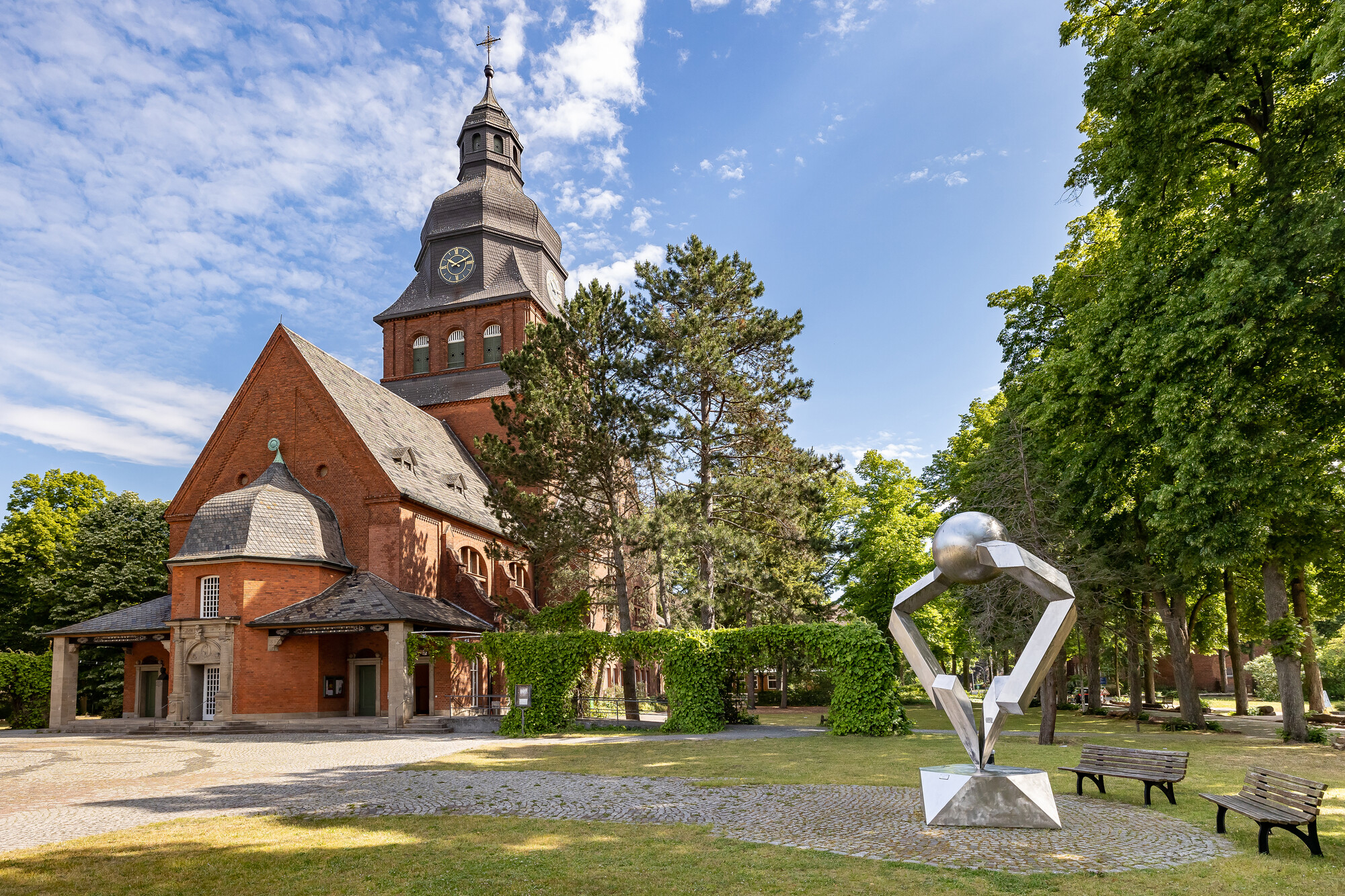 Foto der Stiftskirche von außen mit einer Skulptur an der rechten Seite 
