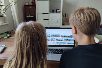 Zwei Kinder sitzen vor einem Laptop und schauen sich Bilder aus Großstädten in Deutschland an.